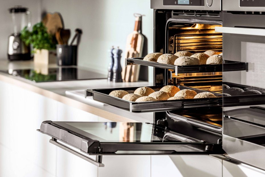 Geöffneter Backofen mit ausgezogenen Backblechen in einer Küchenhochschrankwand